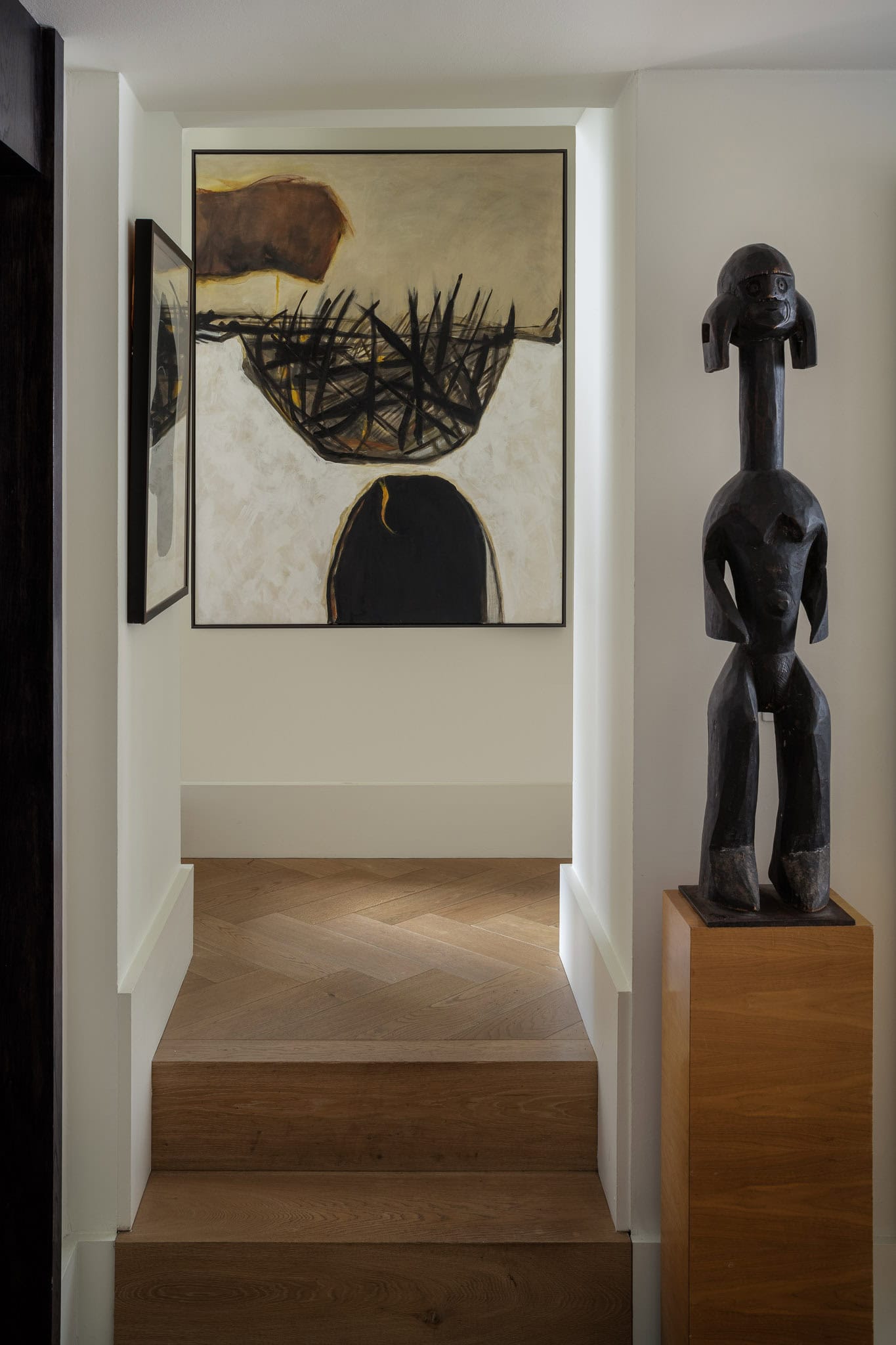 A colourful abstract painting with black wooden sculptures in a modern interior.