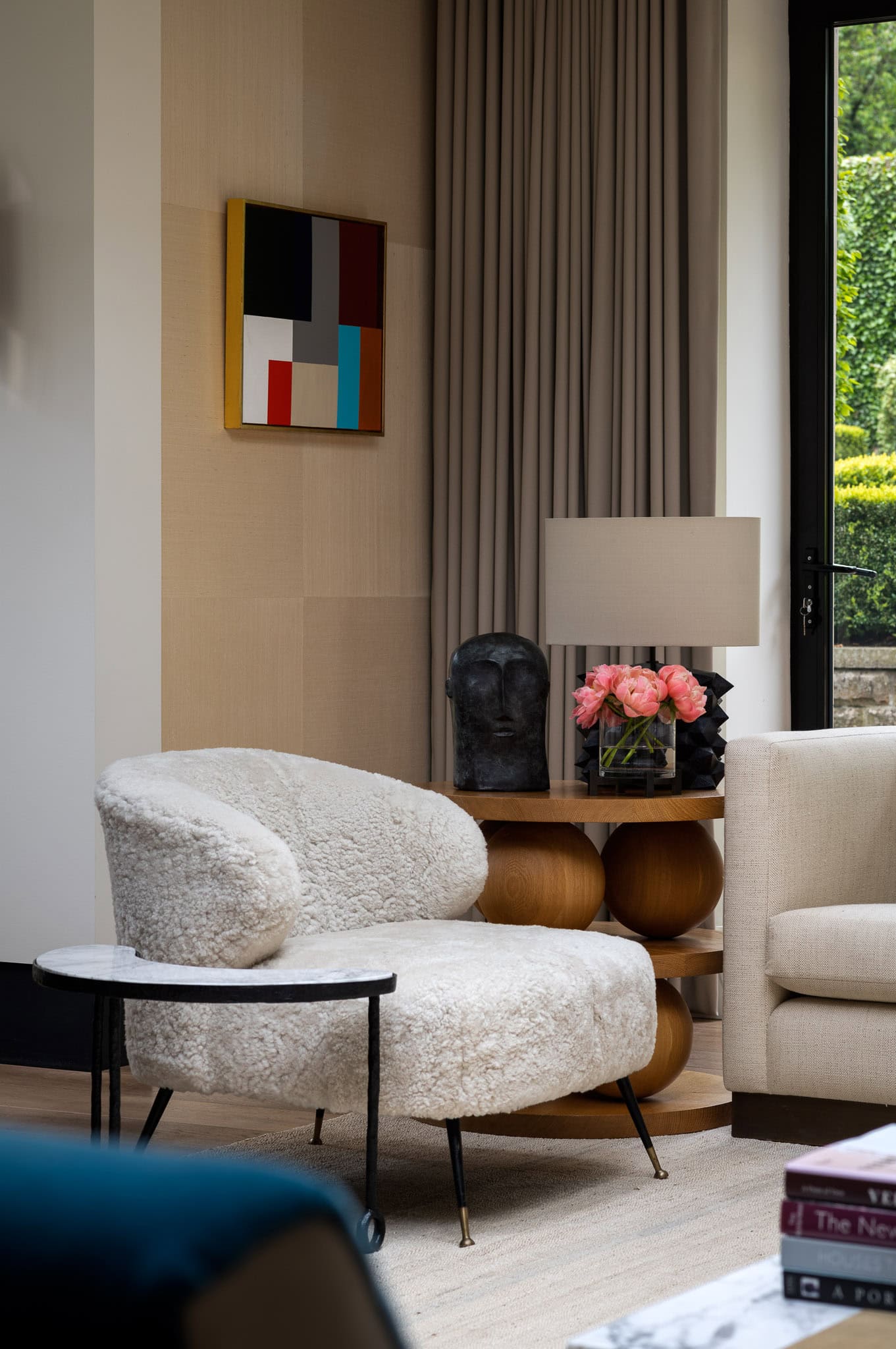Comfortable modern living room with plush armchair, side table with pink flowers, and large window w.