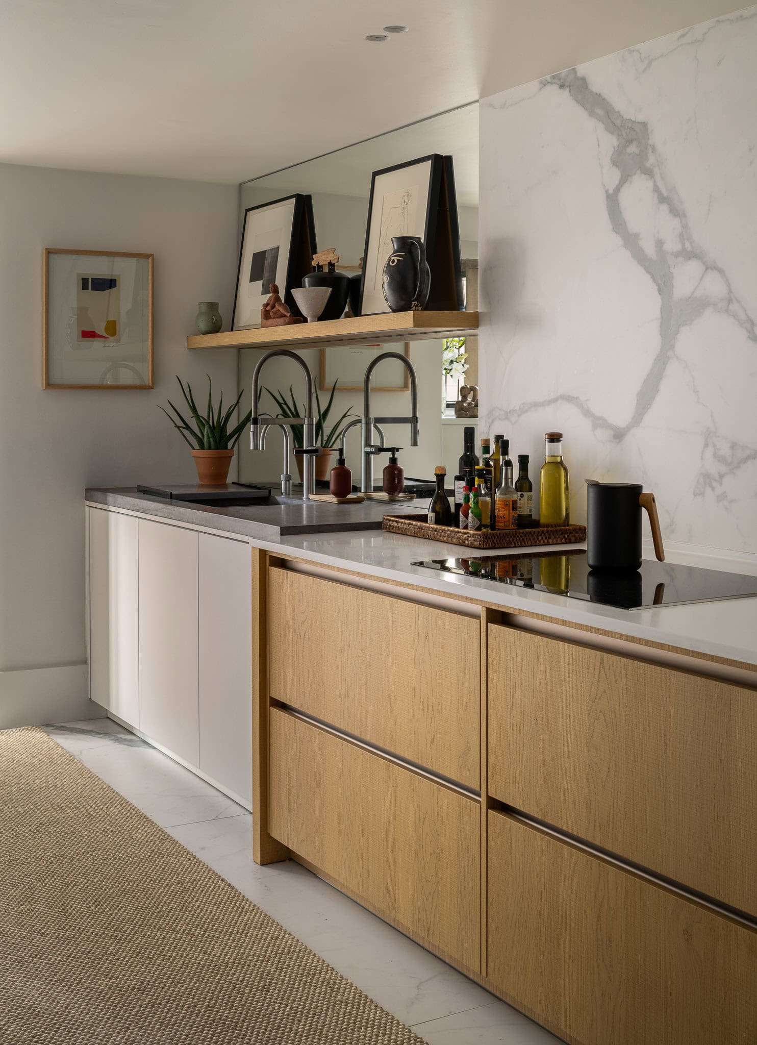 Contemporary kitchen with white and wooden cabinetry, marble backsplash, and stylish decor accents.