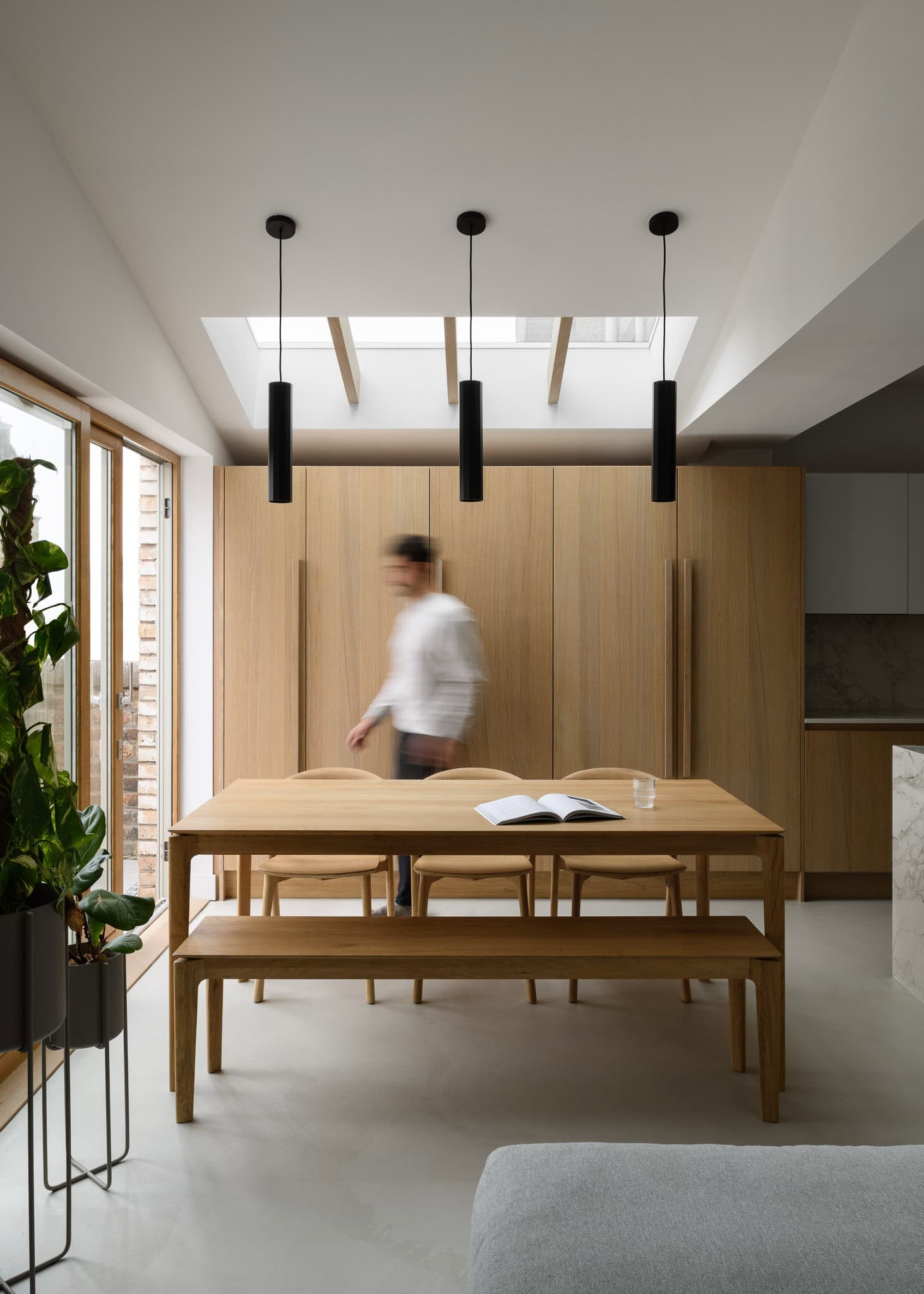 Bright modern dining room with wooden furniture, large windows, and minimalist decor, creating a war.