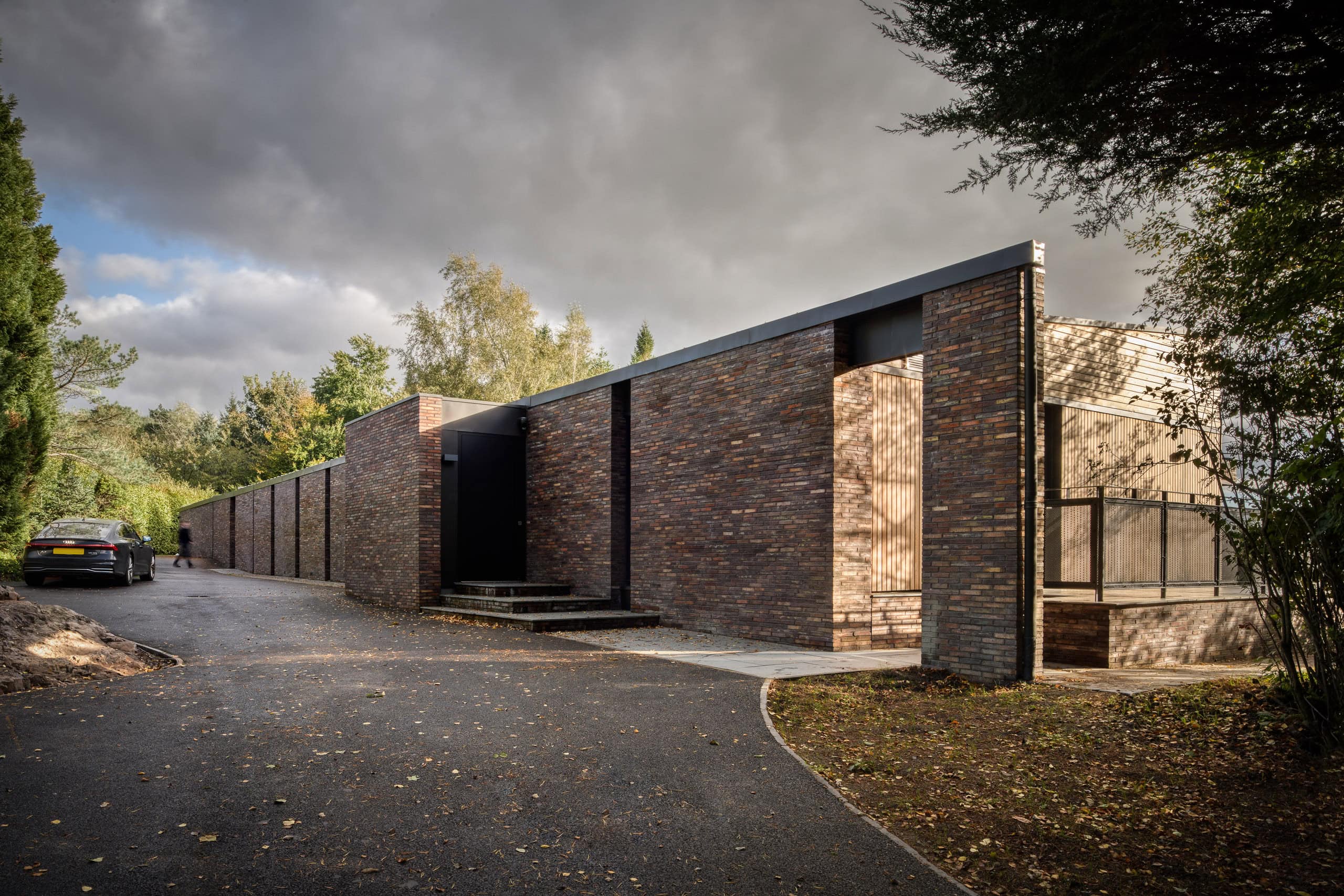 Modern brick residential building with sleek design and large windows, set in a lush green environment.