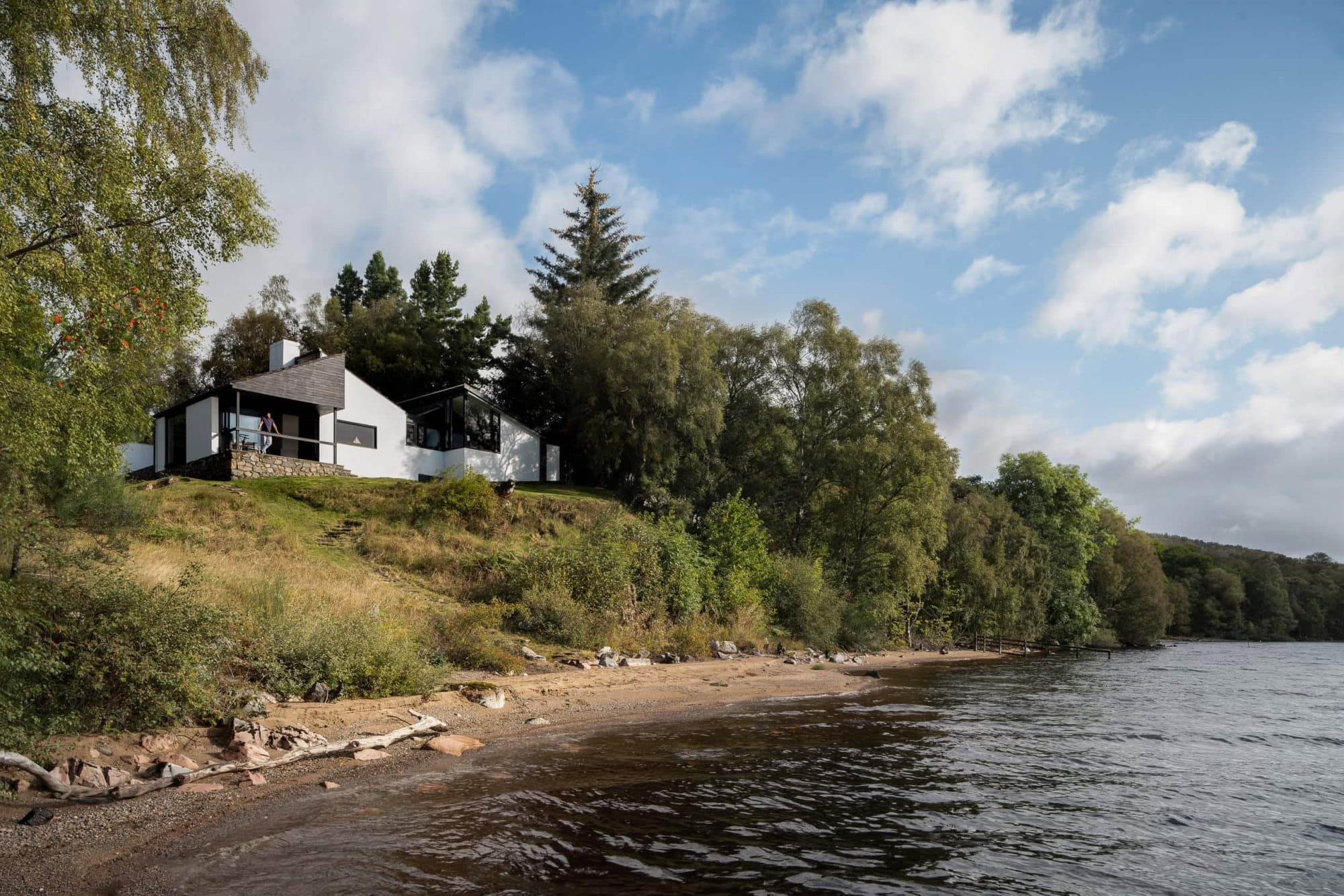 Modernist home with large windows and outdoor terrace in a natural setting by Loch Rannoch