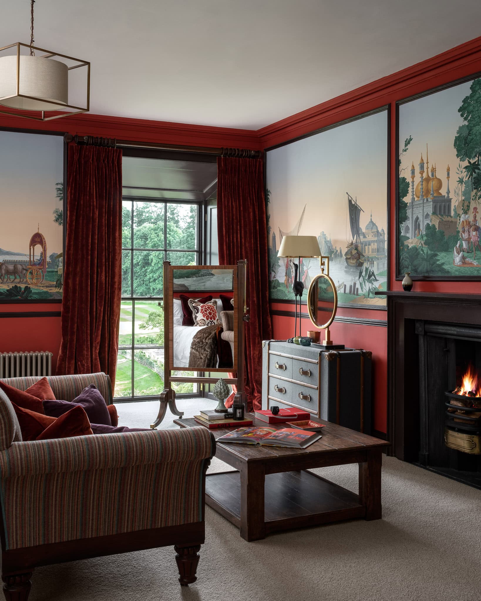 Elegant living room with mural wall art, fireplace, and vintage furniture, creating a cosy and styli.