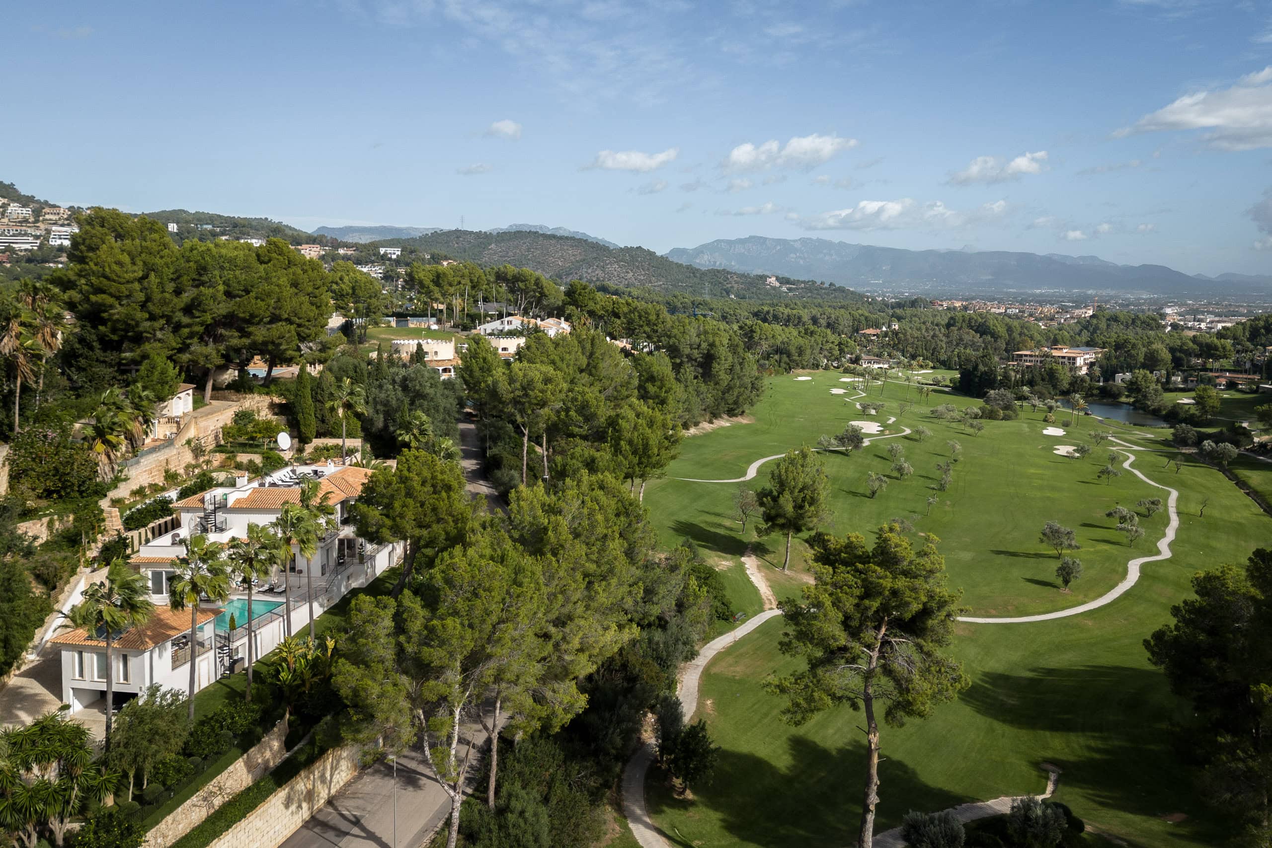 aerial shot of son vida golf course with lush greenery and surrounding residential area under a blue sky.