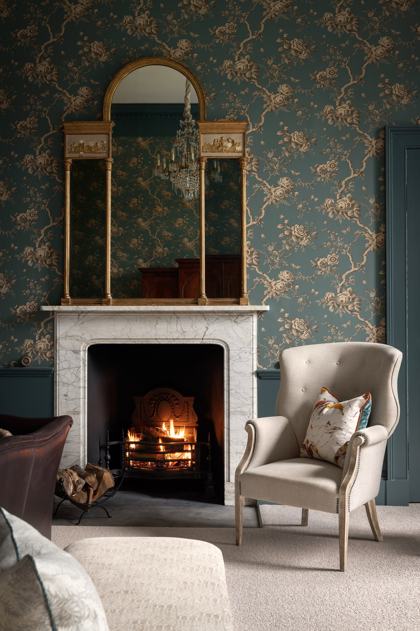 Elegant living room with vintage wallpaper, marble fireplace, and classic armchair for cosy comfort.