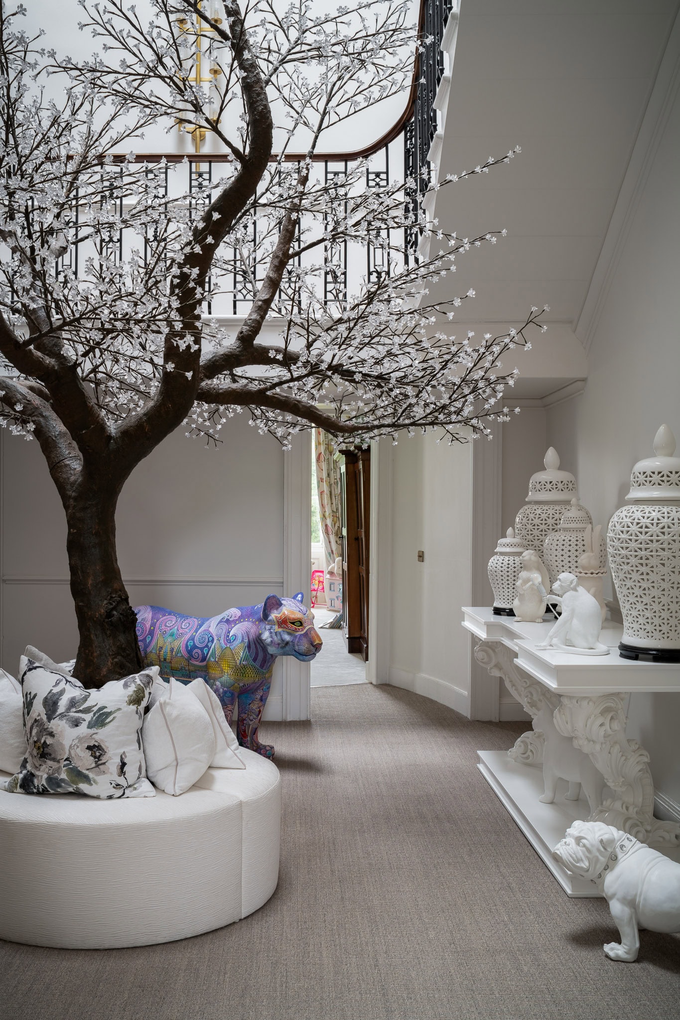 A colourful artificial tree with white blossoms inside a stylish living room.