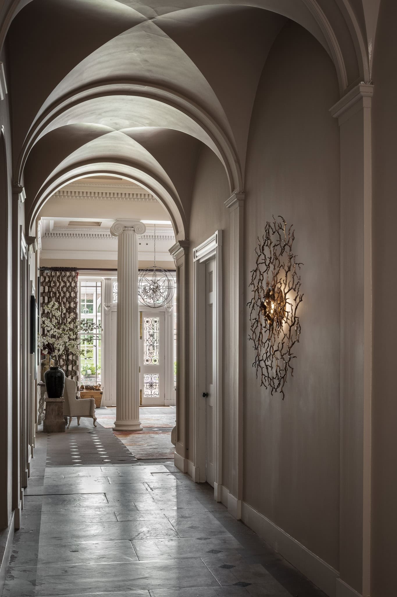 Elegant hallway with arched ceilings and classic decor, featuring a grand entrance and stylish wall.