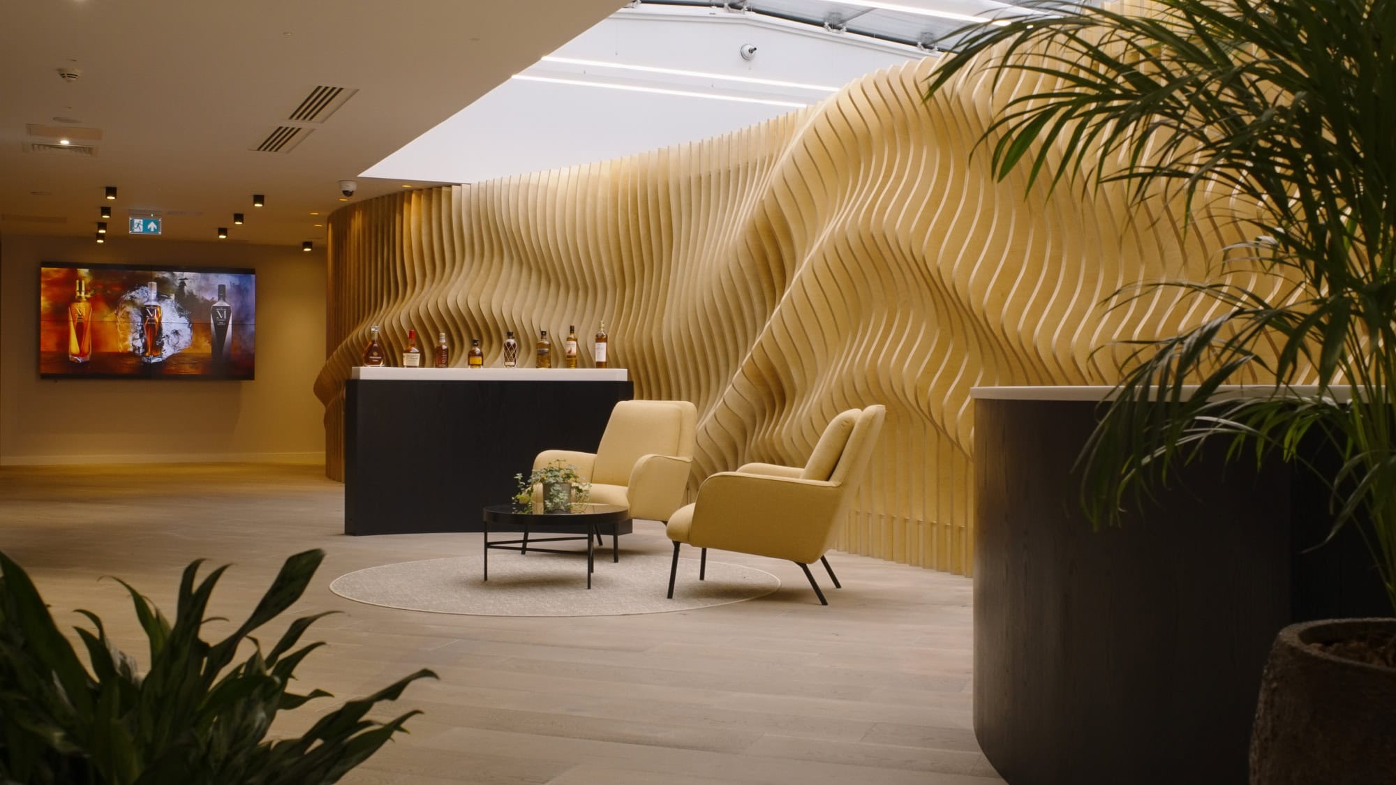 Contemporary entrance hall at Edrington headquarters in Glasgow designed by S&Co, featuring sculptural timber wall detailing, lounge seating, and warm ambient lighting.