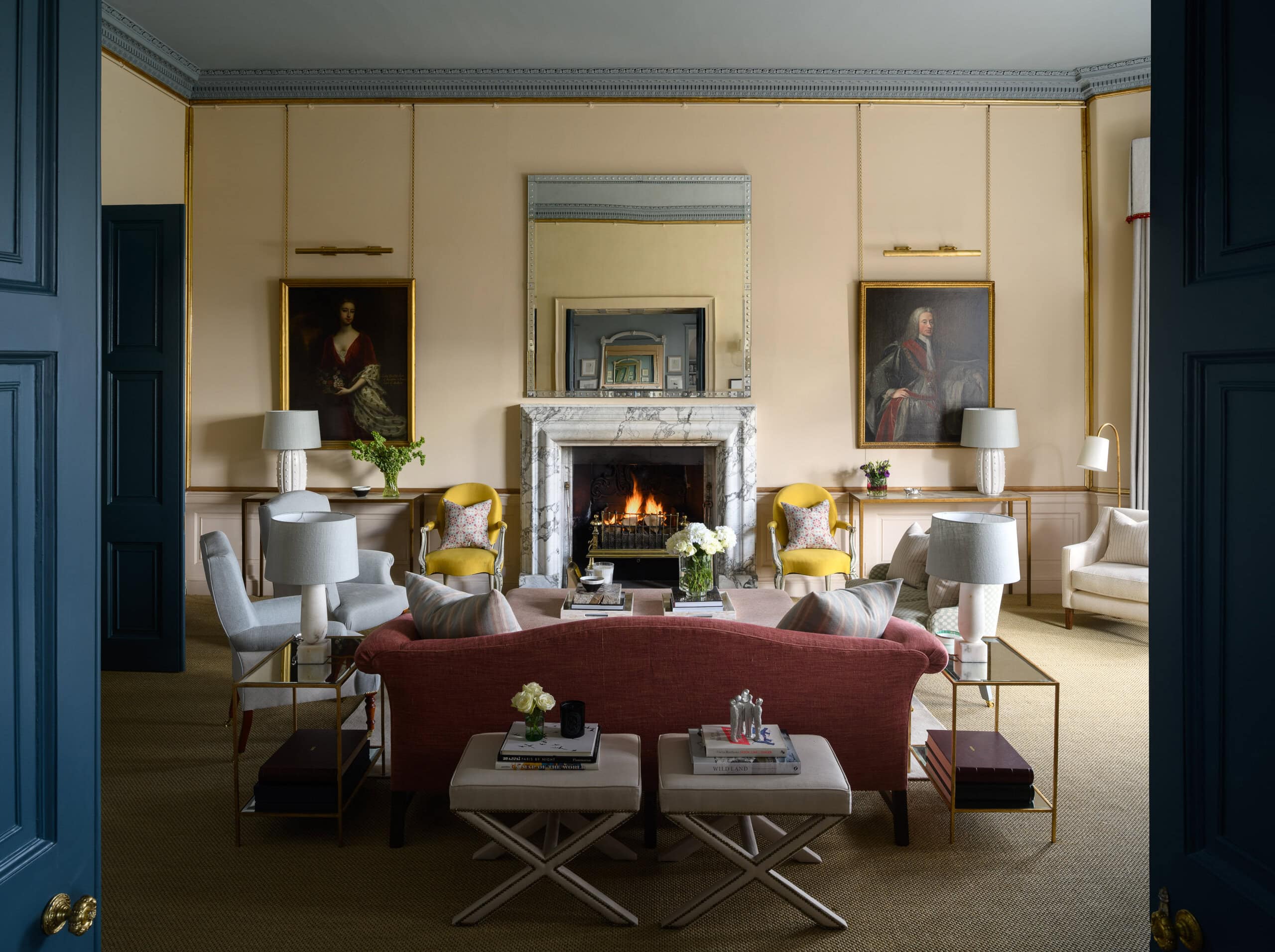 Elegant lounge interior at Eildon Hall designed by Olivia Emery featuring a marble fireplace, period portraits, soft pastel furnishings, and symmetrical classical detailing.