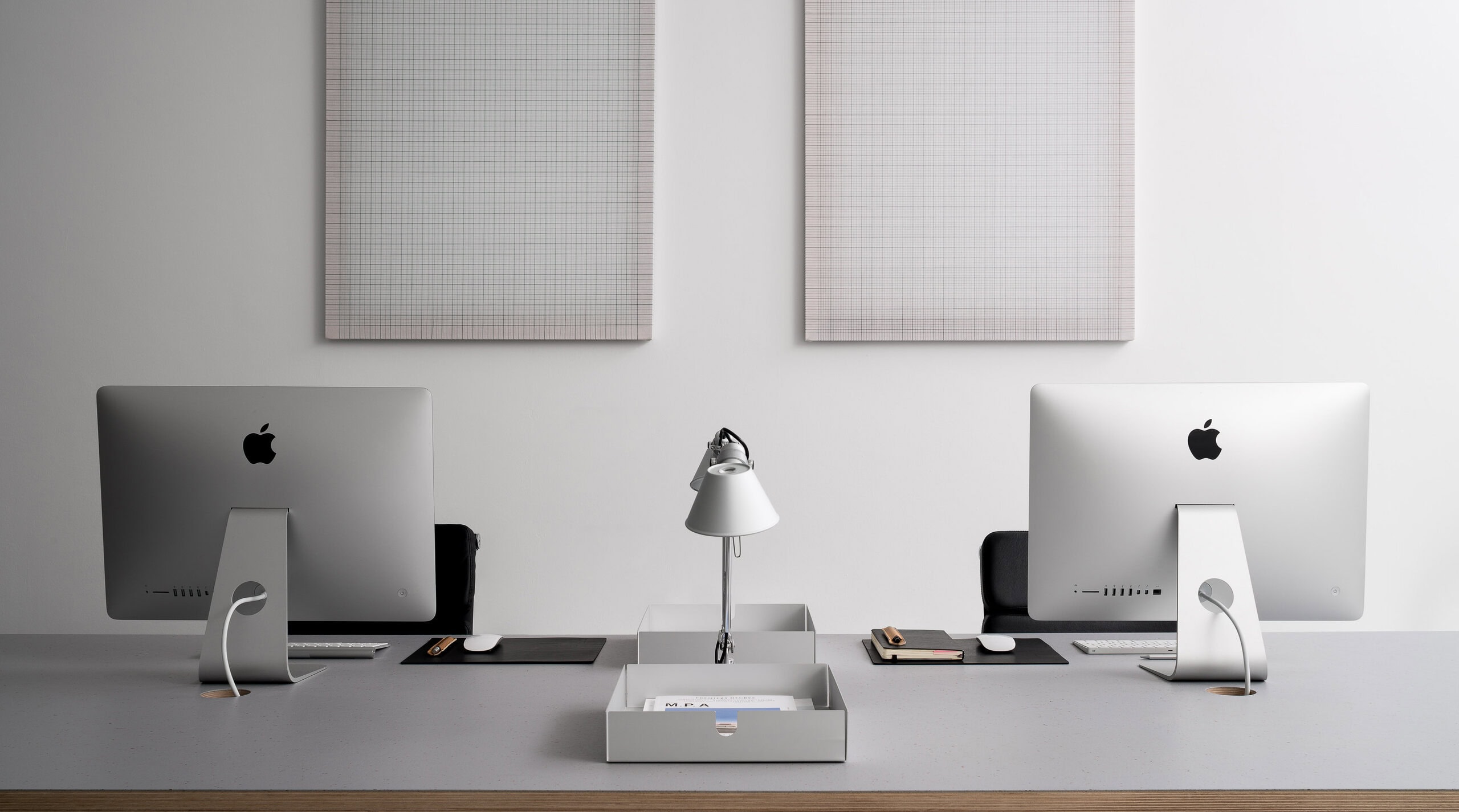 Minimalist office workspace at Instrument Applied Design Shop in Glasgow featuring twin Apple iMac desks, soft neutral interiors, and contemporary wall-mounted textile artwork.