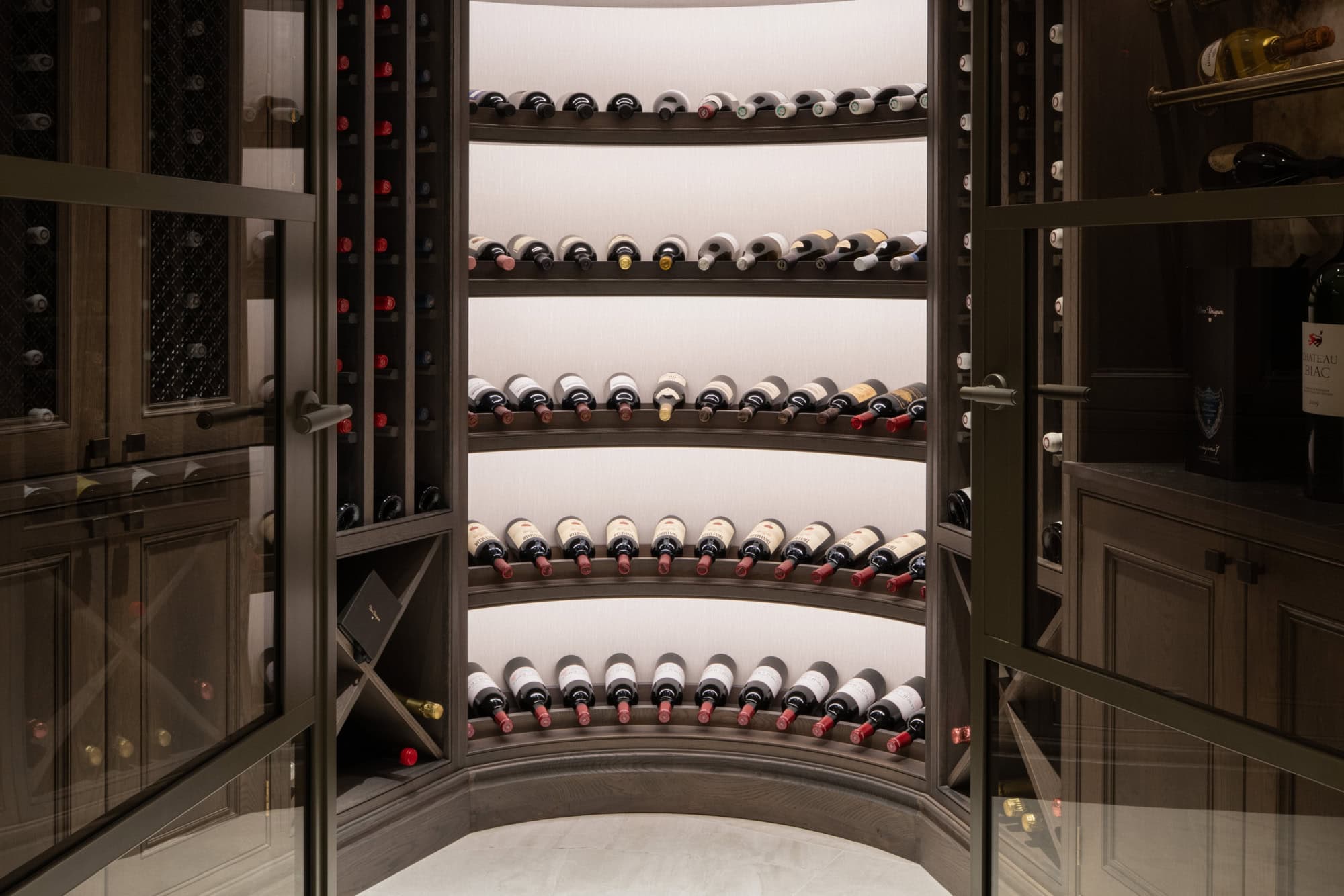 Bespoke wine cellar interior designed by Megan Wisely Interiors for a luxury home in Dunblane, featuring curved illuminated shelving and dark timber cabinetry.