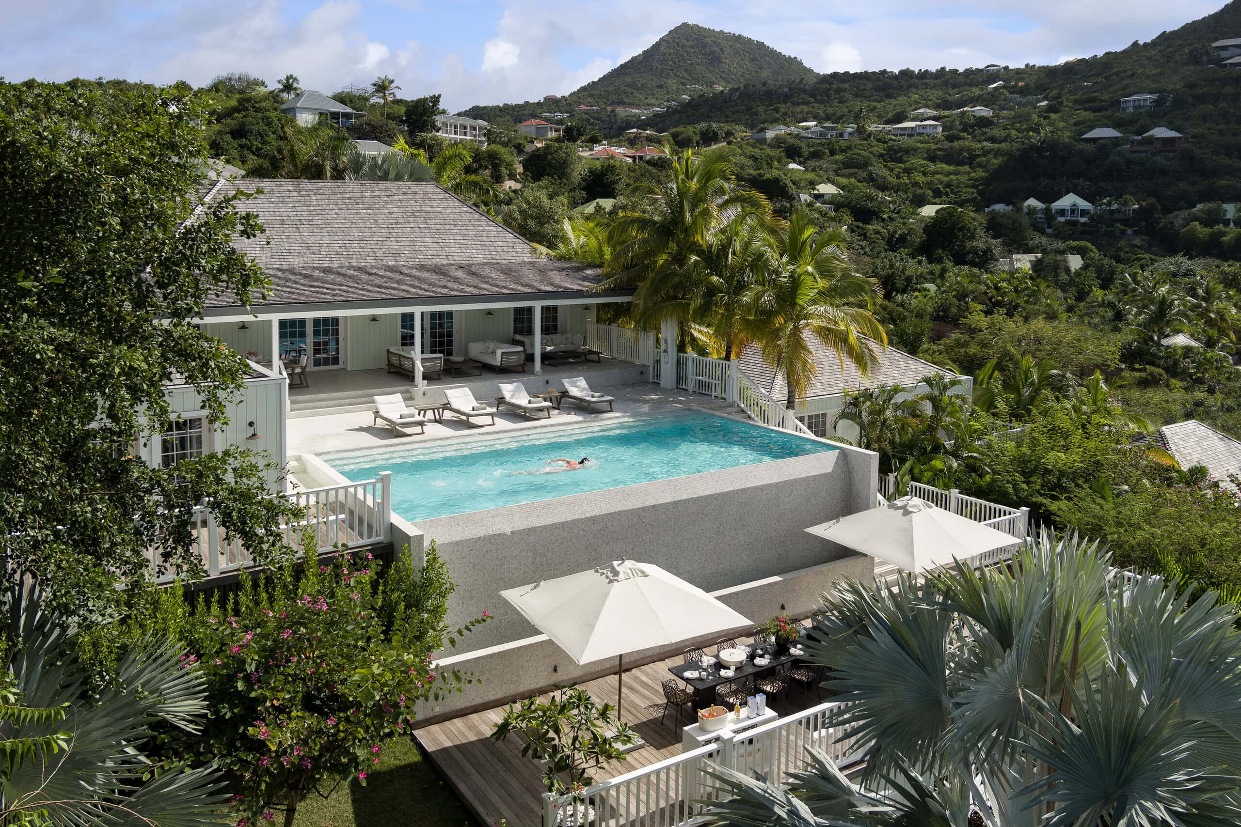 Luxury hillside villa in Saint Barthélemy featuring an elevated infinity pool, tropical landscaping, and panoramic Caribbean mountain views.