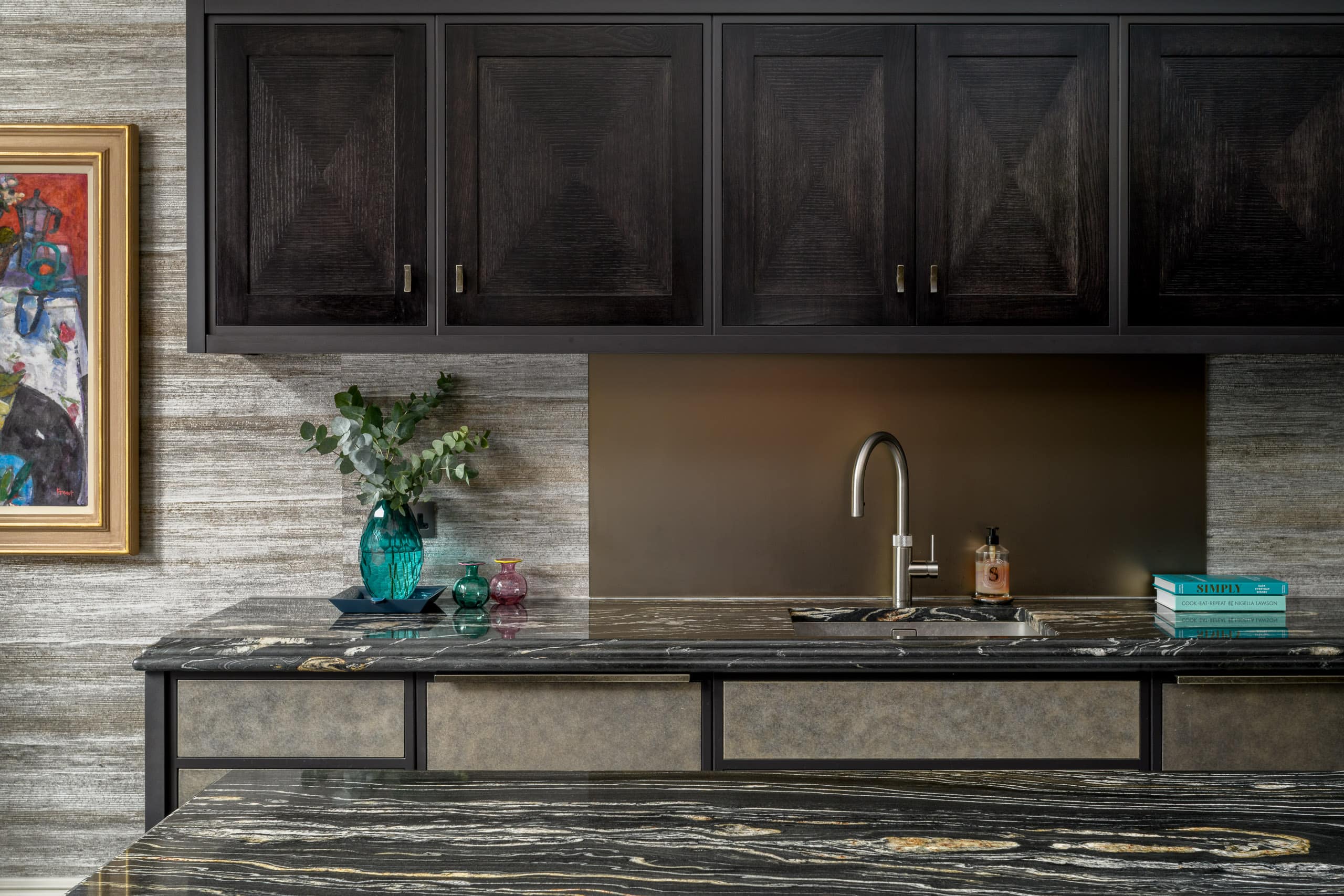 Modern kitchen with dark cabinets, marble countertop, and decorative items.