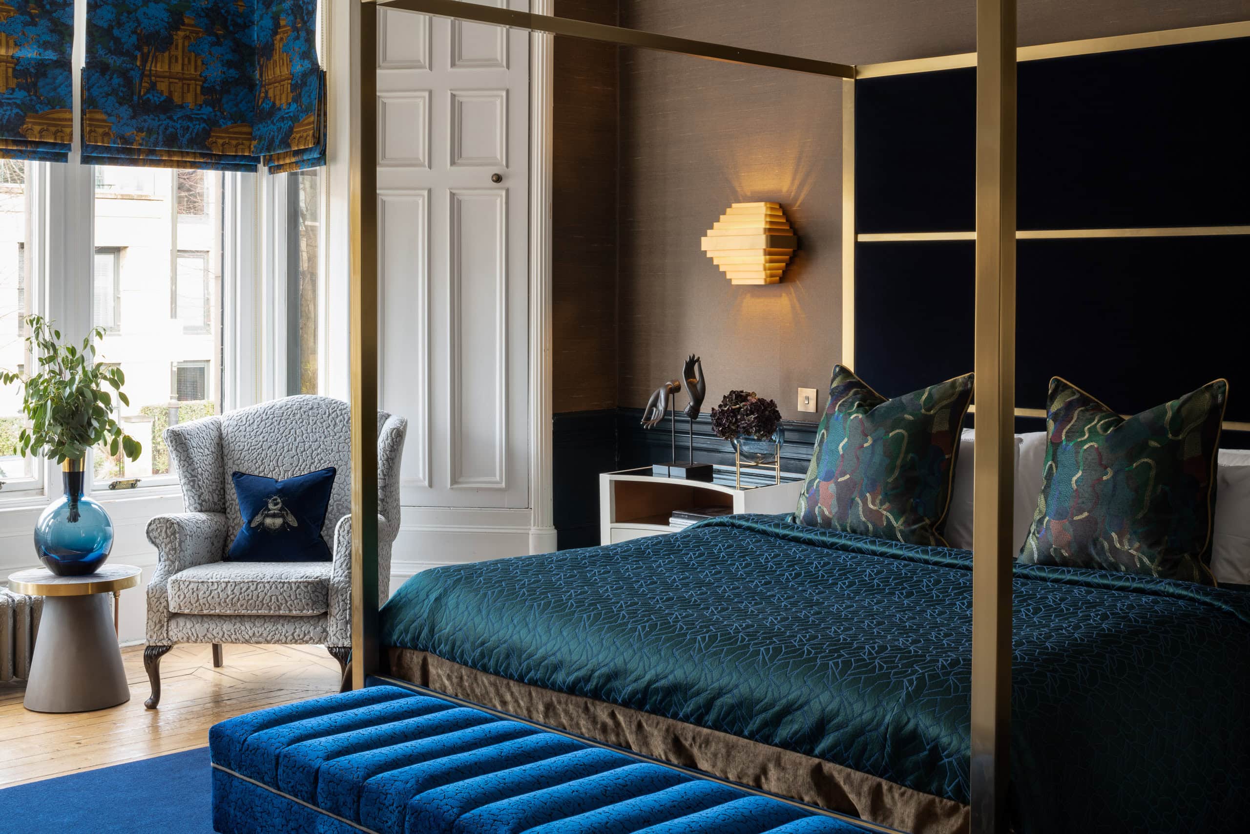 Elegant bedroom with blue accents, modern decor, and natural light from large windows.