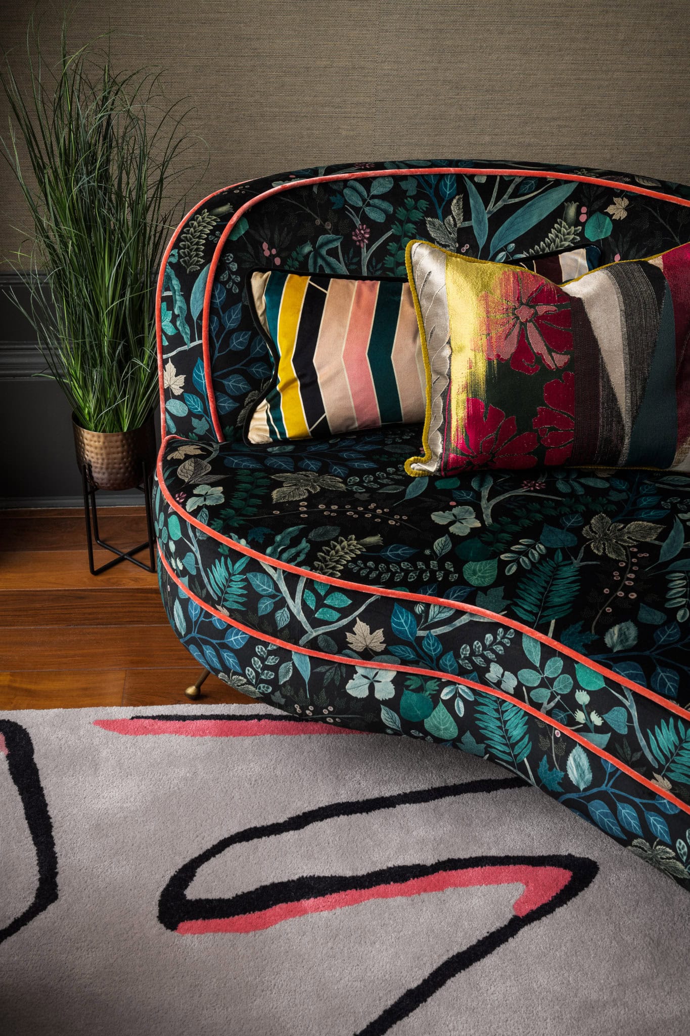 Interior shot of a floral patterned sofa with colourful cushions and green plant.