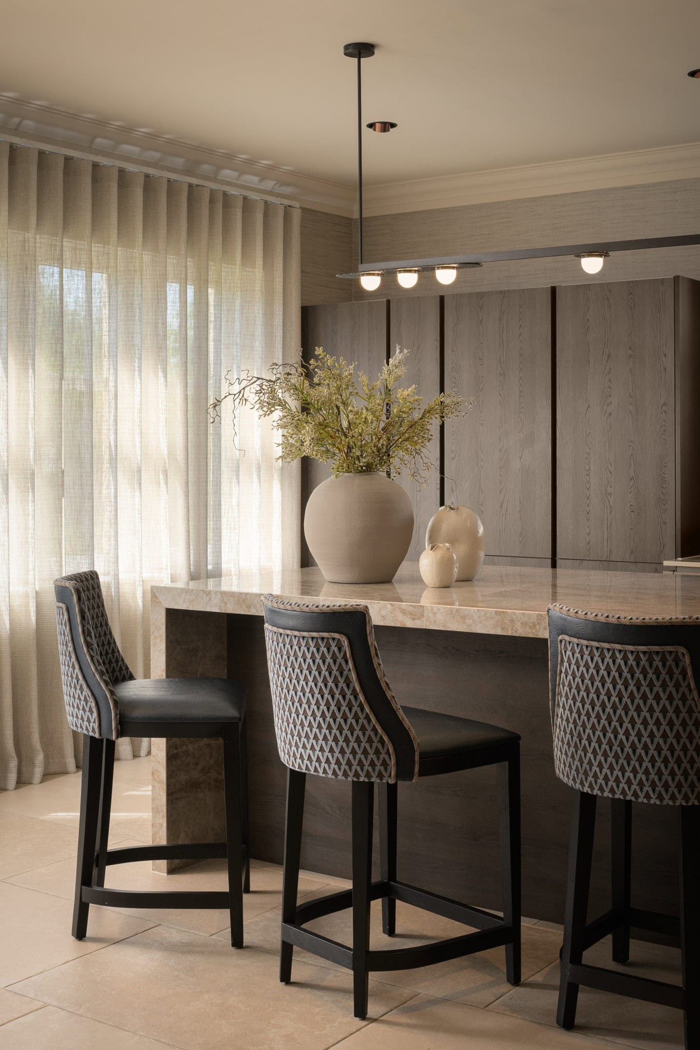 Modern kitchen with marble island, pendant lighting, and grey cabinetry.