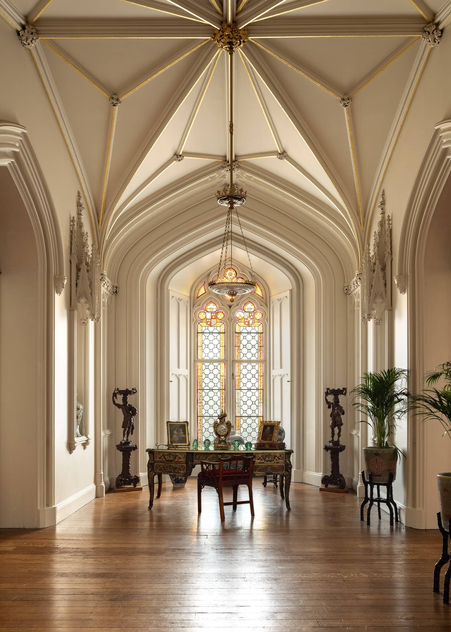 Elegant historic interior with ornate ceiling and large stained glass window.