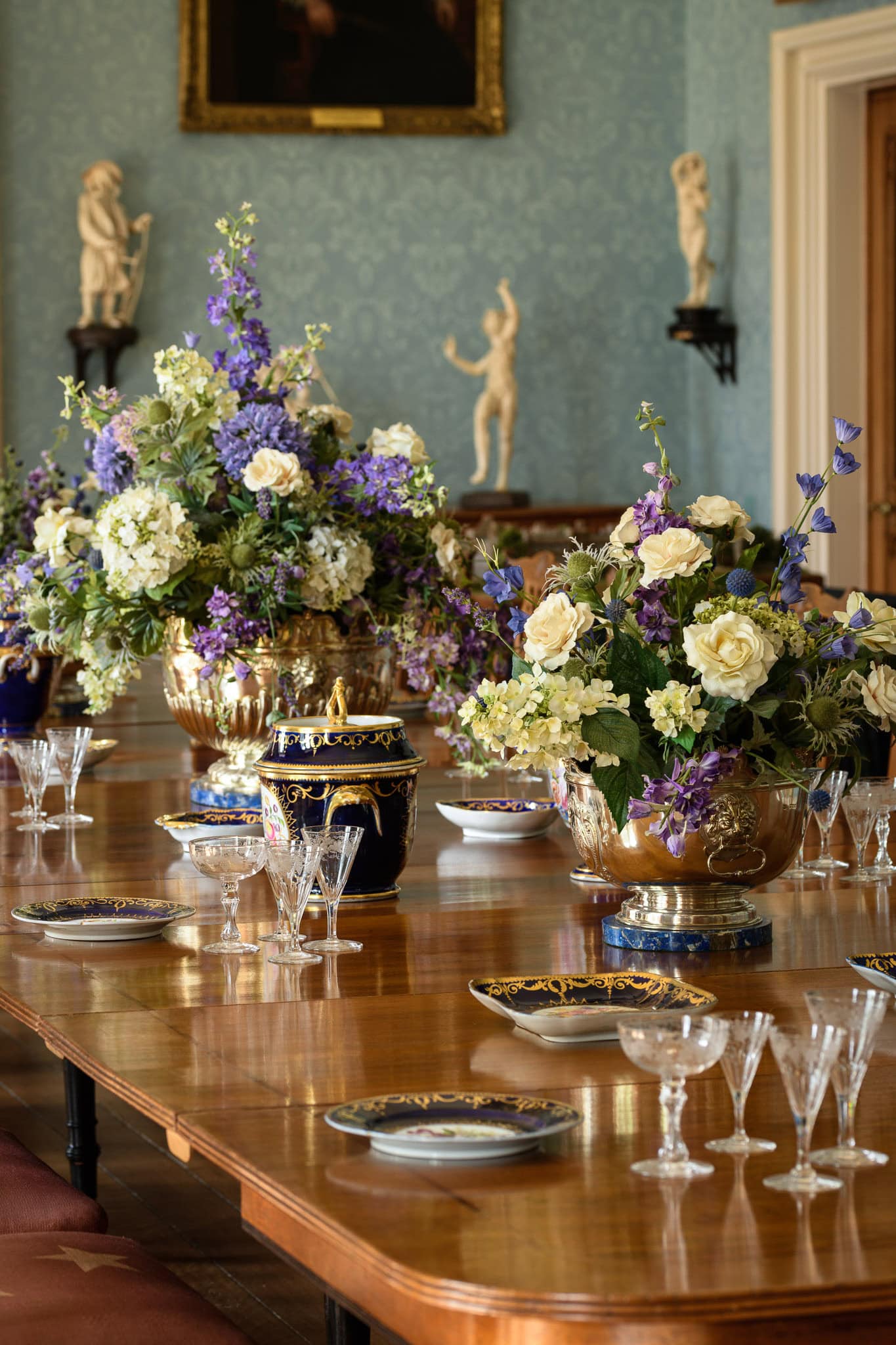 Elegant floral arrangement on a polished wooden dining table in a classic interior setting.