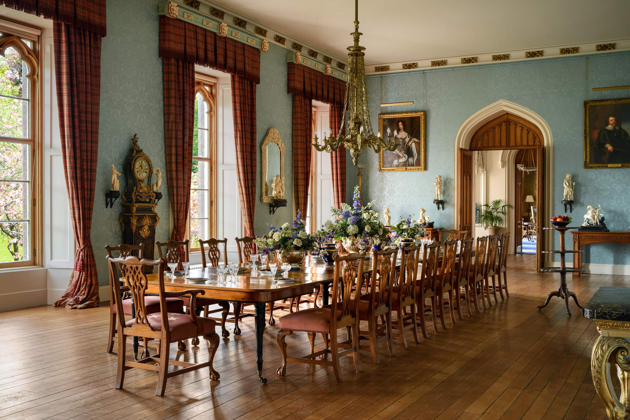 Elegant historic dining room with large wooden table and floral centrepiece.