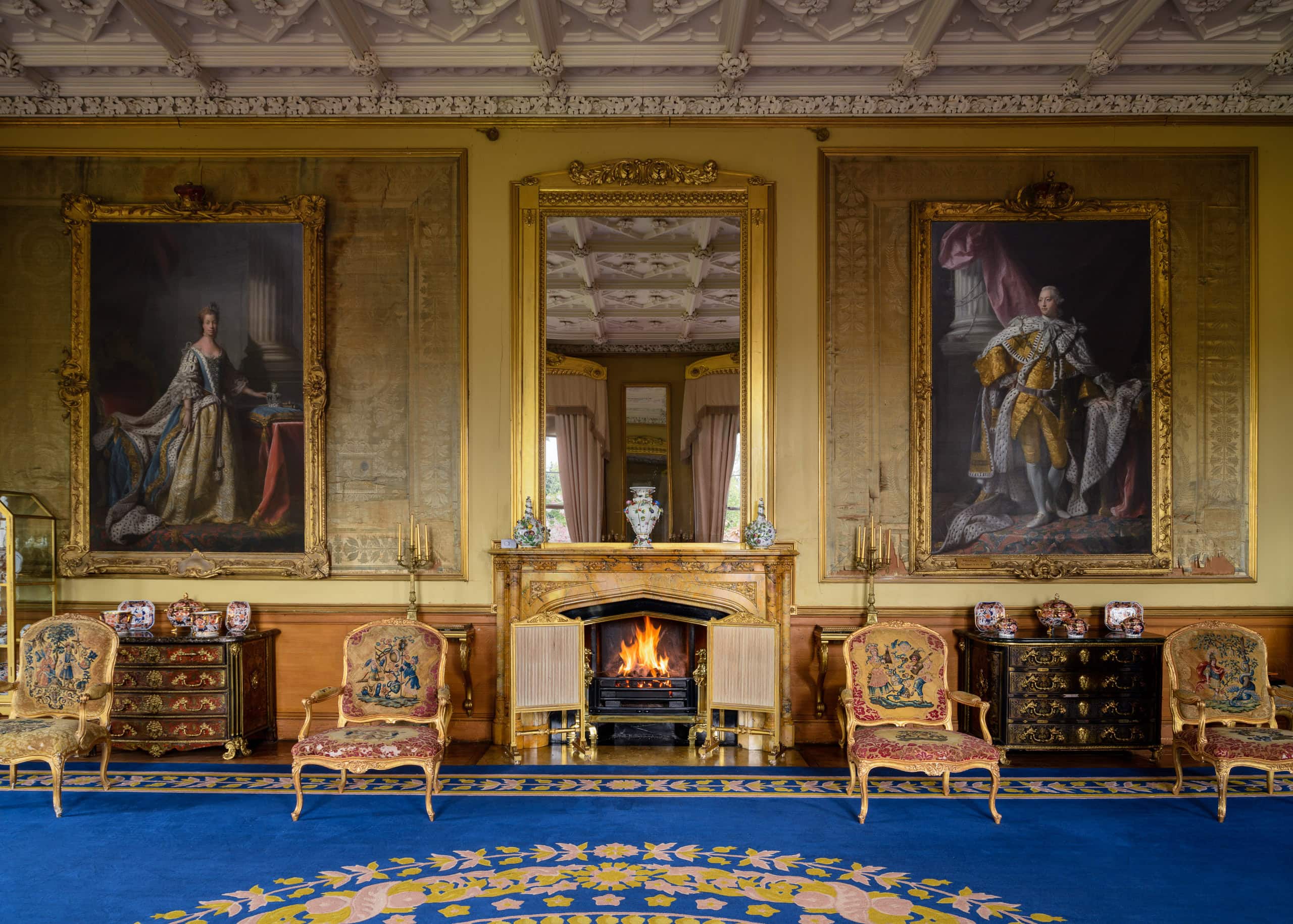 Elegant historic interior with portraits, ornate furniture, and a fireplace.