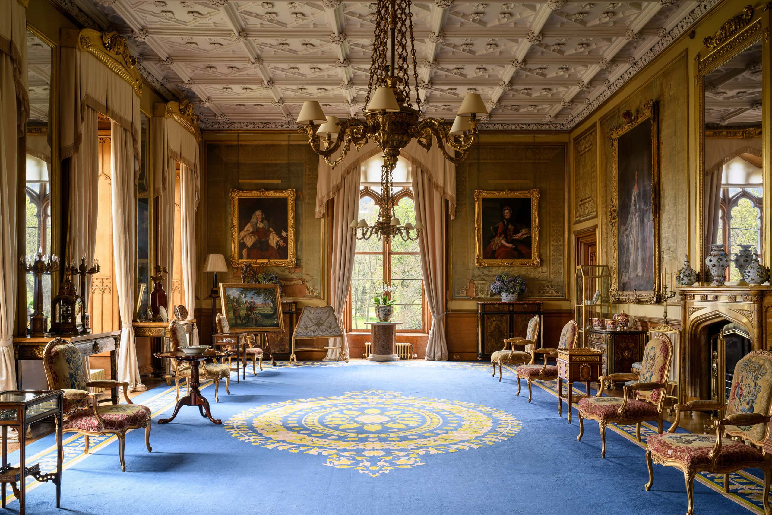 Elegant historic room with ornate decor, chandeliers, and antique furniture.