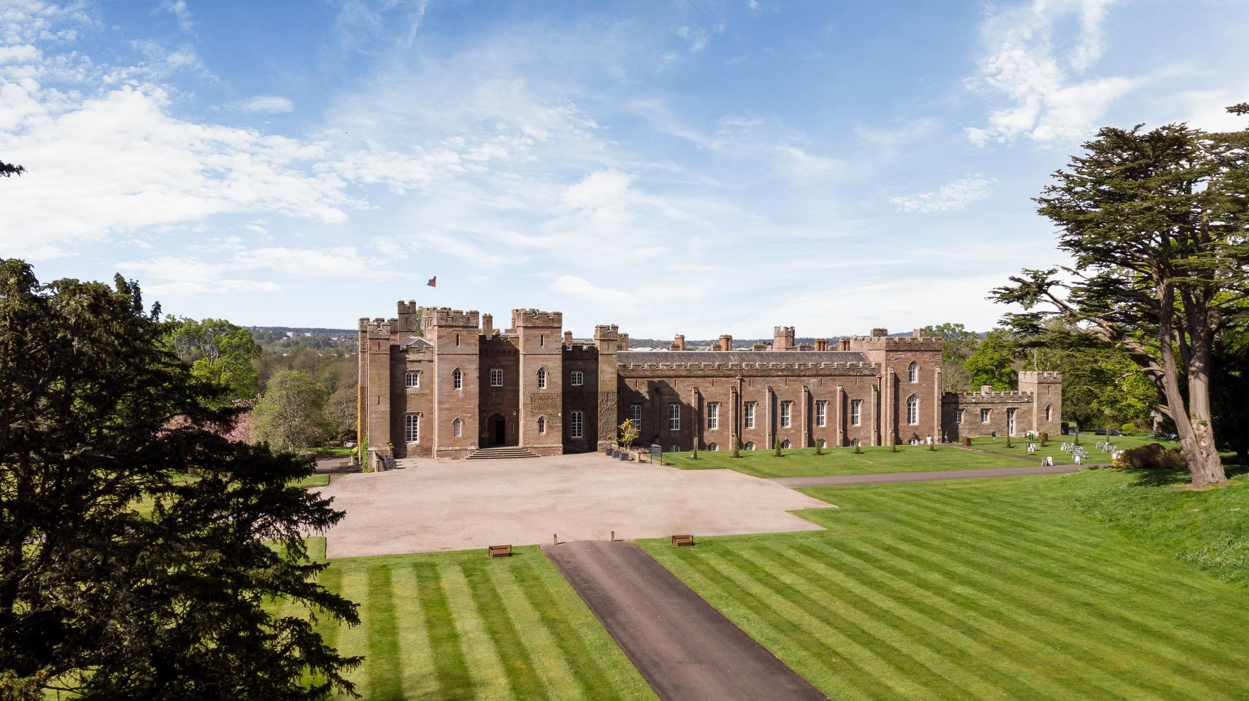 Exterior view of a historic castle with lush green lawns and a clear blue sky.