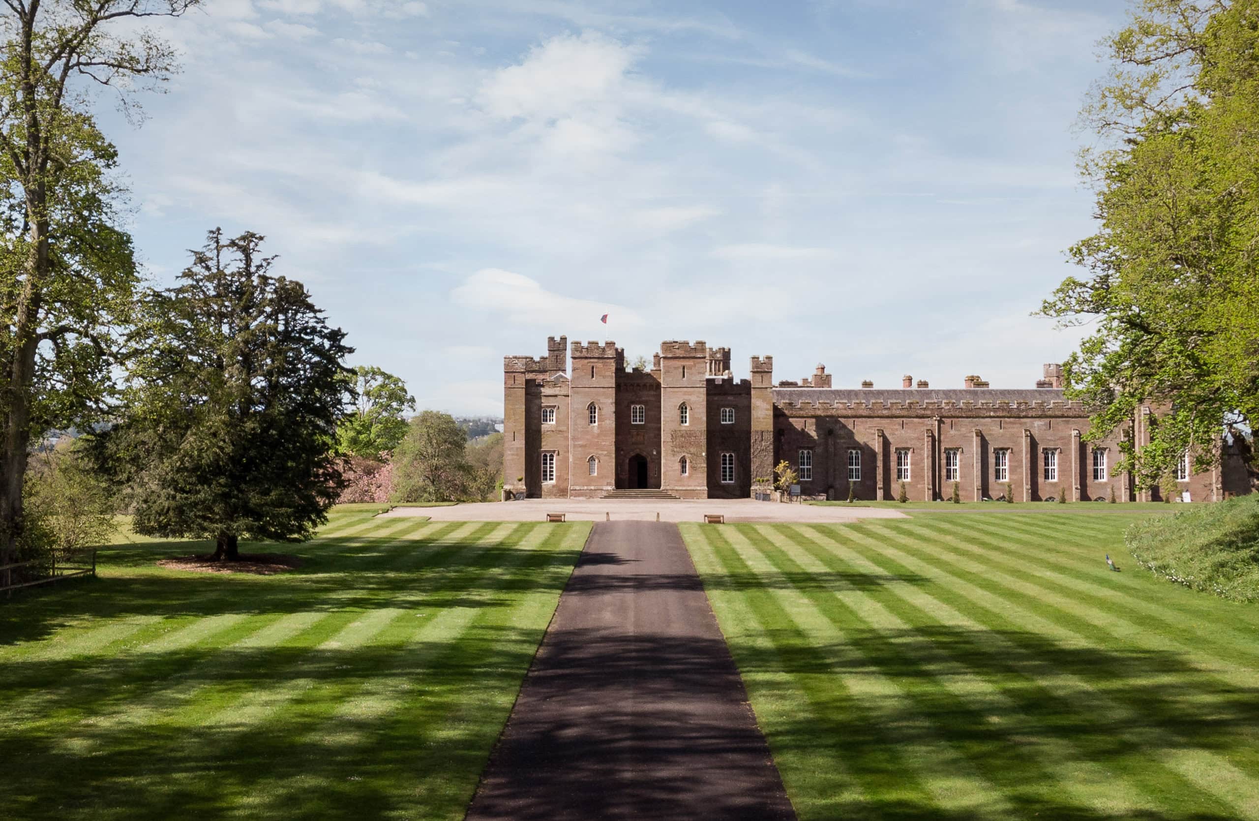 Historic castle with lush green grounds and a clear blue sky.