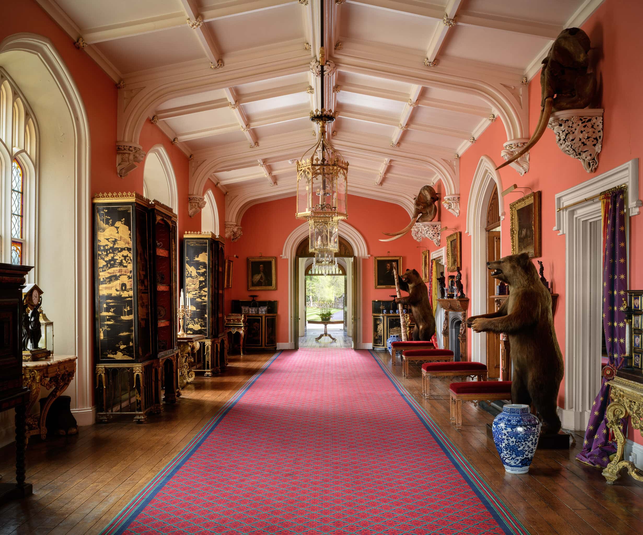 Elegant historic interior with taxidermy animals and ornate decor in a pink-walled gallery.