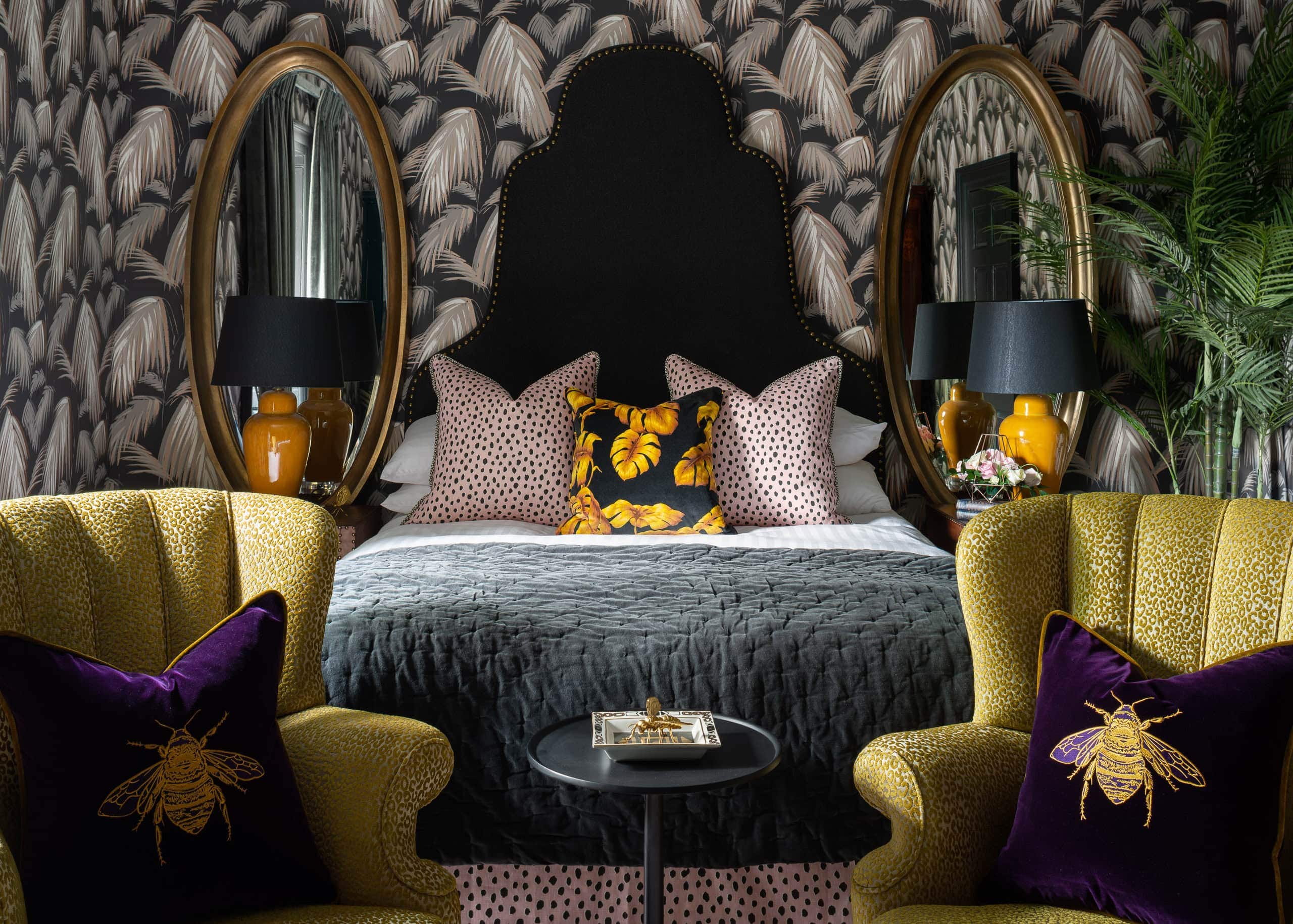 Elegant bedroom interior with bold wallpaper, gold accents, and bee-themed cushions for a luxurious,.