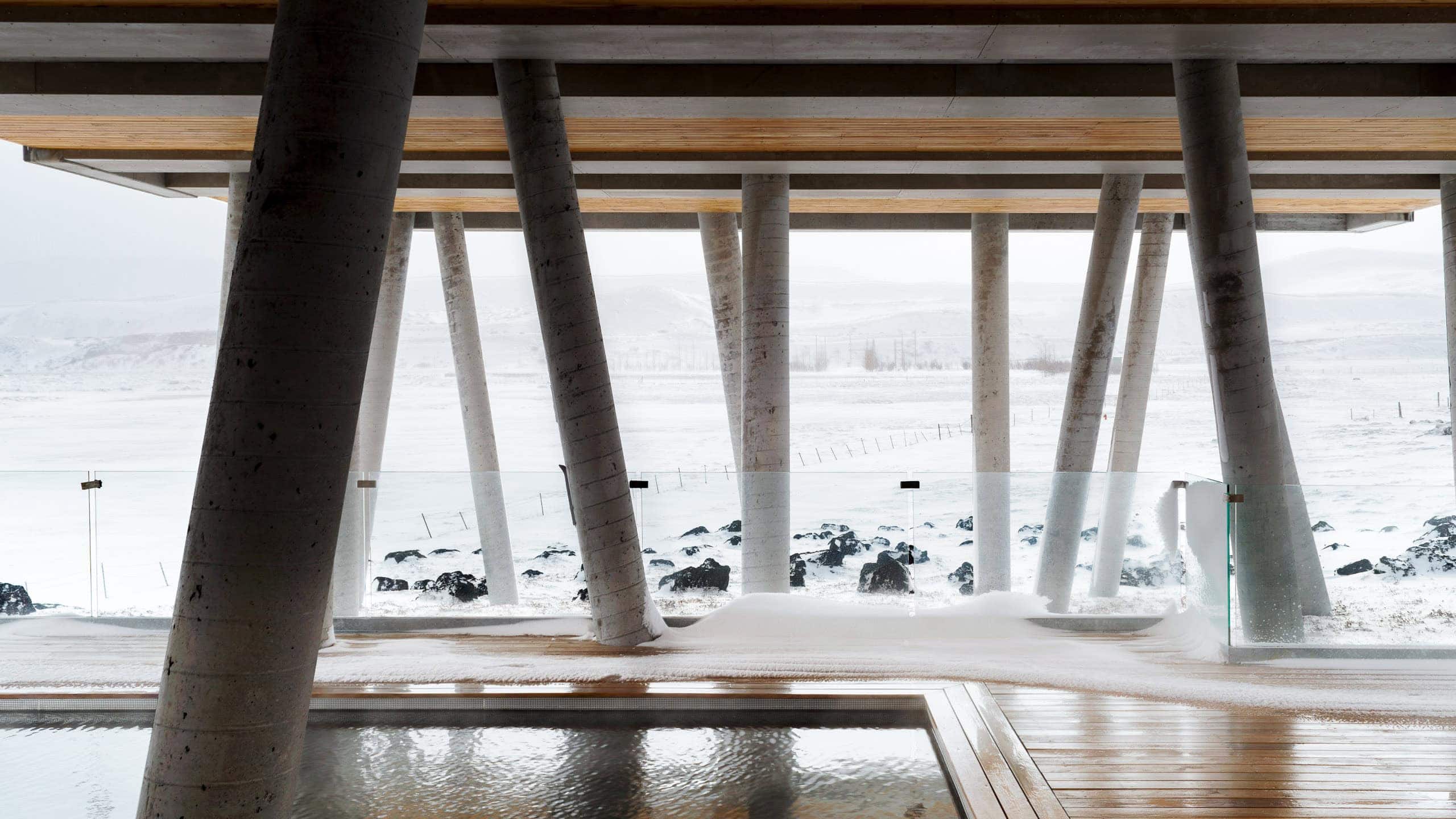 Modern architectural structure with large supporting columns over a snowy landscape in winter.