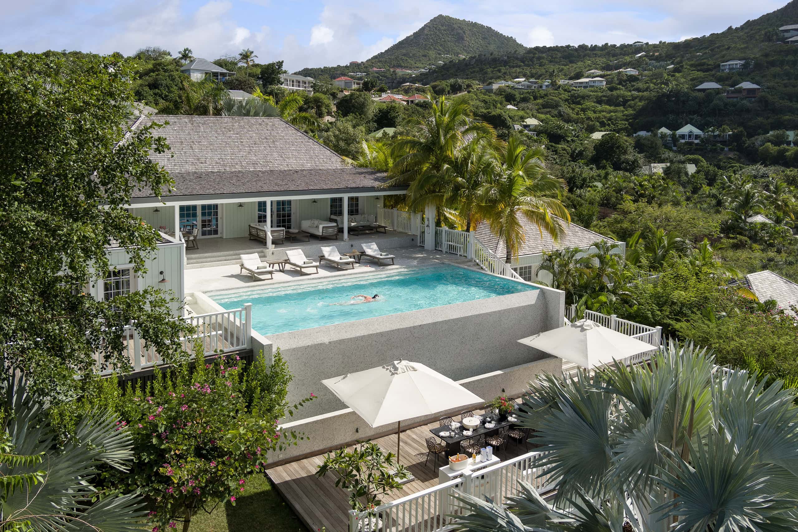 Luxurious private villa with infinity pool overlooking lush tropical landscape in the Caribbean.